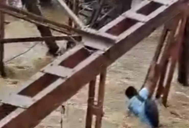 hombre cuelga de un puente que es tragado por el agua.png