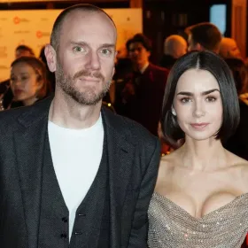 Una pareja de esposos con vestido de gala en un evento publico posando en la alfombra roja
