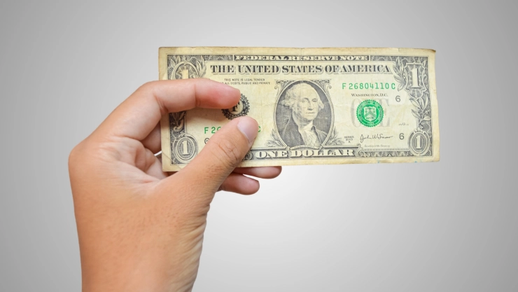 Una persona sostiene un billete de un dólar estadounidense