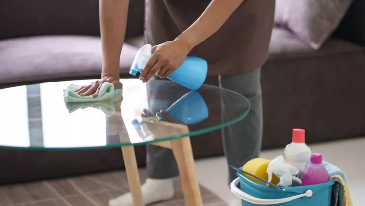 Una empleada doméstica limpia una mesa.
