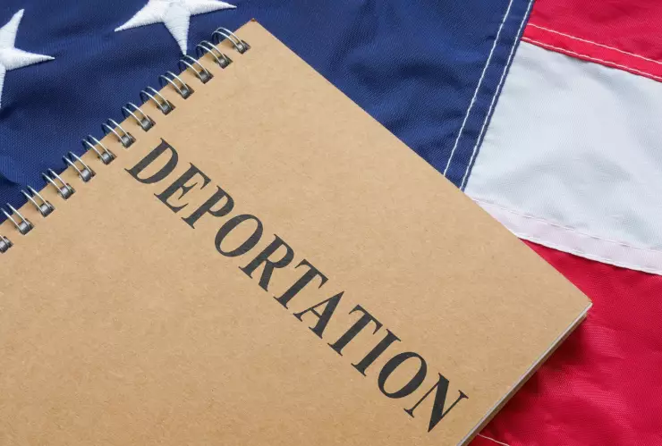 Una libreta con el nombre deportación sobre una bandera estadounidense.