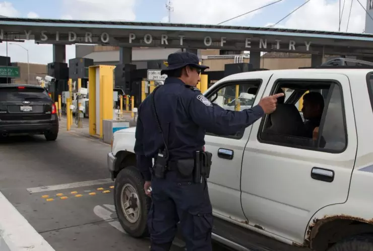 Un oficial de la CBP dirige a los coches en un puerto de entrada.