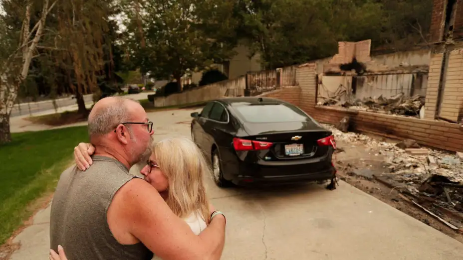 Una pareja frente a su casa quemada por incendios forestales en Washington.