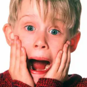 Niño con sueter gritando con las manos en el rostro