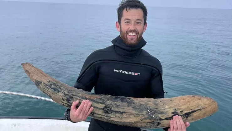 Alex Lundberg posa con el colmillo de mastodonte que encontró en Florida.