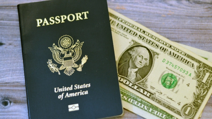 Un pasaporte estadounidense junto a billetes de dólar.
