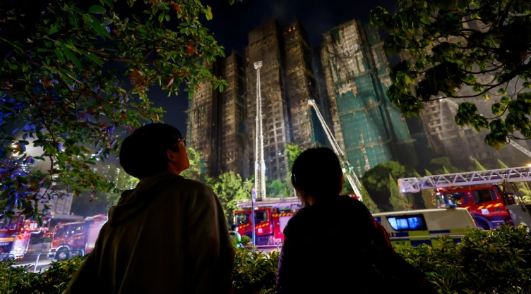 Foto de la gente se encuentra cerca de la escena de un incendio mortal, que estalló ayer en el complejo de viviendas Wang Fuk Court, mientras los bomberos continúan los esfuerzos para extinguirlo, en Hong Kong , China, el 27 de noviembre de 2025.