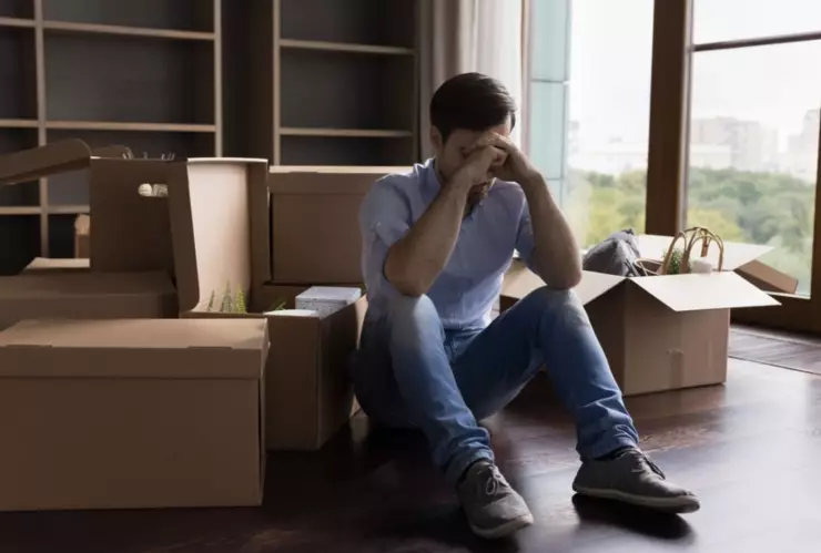 Un hombre está sentado junto a unas cajas de mudanza.