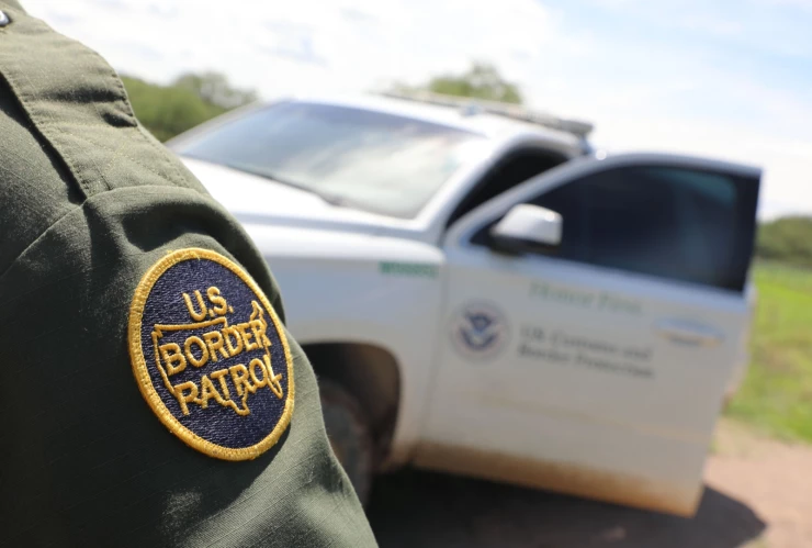 Agente de la CBP frente a patrulla.