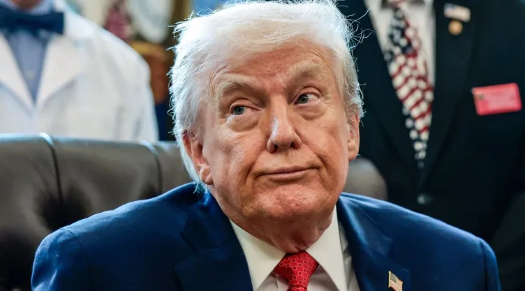 Donald Trump aparece sentado durante un evento oficial en la Casa Blanca, mientras responde preguntas de la prensa.