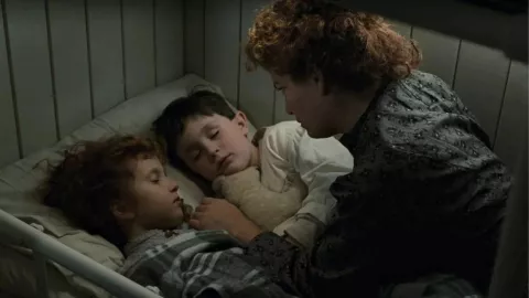 En la imagen, un frame de la película donde aparece Reece Thompson en la escena donde su madre lo acuesta para dormir.