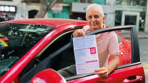 Un hombre muestra su boleta de la tenencia vehicular como muestra de su pago en Edomex 2025.