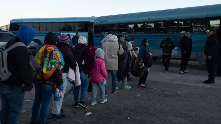 Un grupo de migrantes hace una fila para subir a unos buses que los llevarán a otros estados de Estados Unidos.