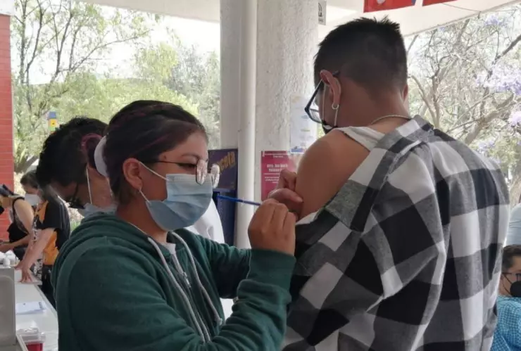 personal médico administrando la vacuna de COVID-19 en el brazo izquierdo de un hombre