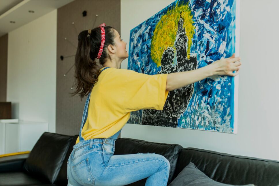 mujer colgando arte en su sala