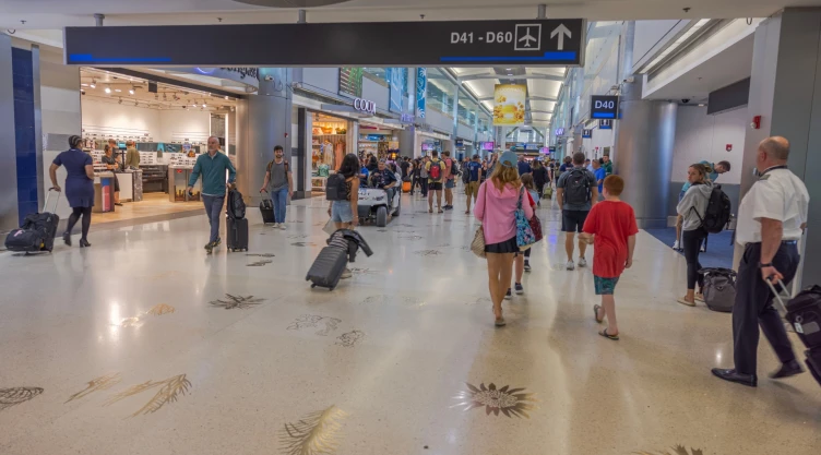 unos pasajeros transitando por los pasillos del aeropuerto de Miami