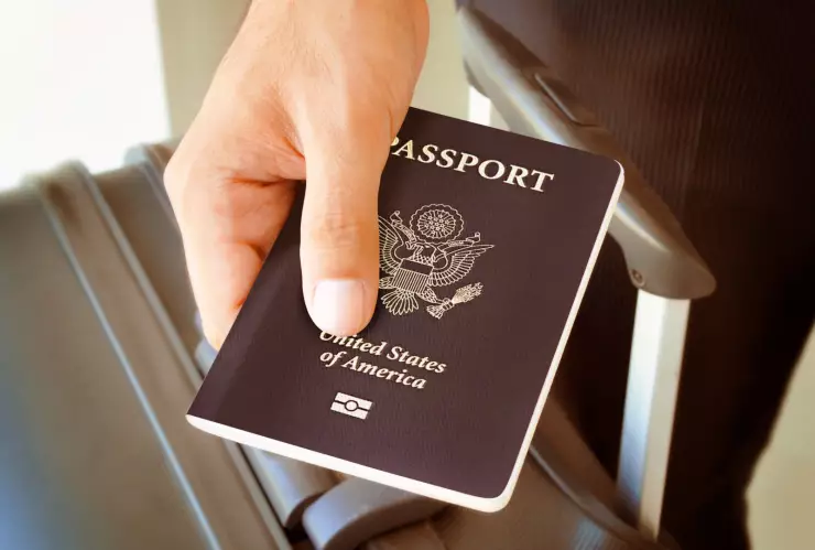 Un hombre lleva el pasaporte estadounidense en la mano.