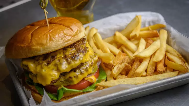 una deliciosa hamburguesa con doble carne y queso fundido acompañado de papas fritas