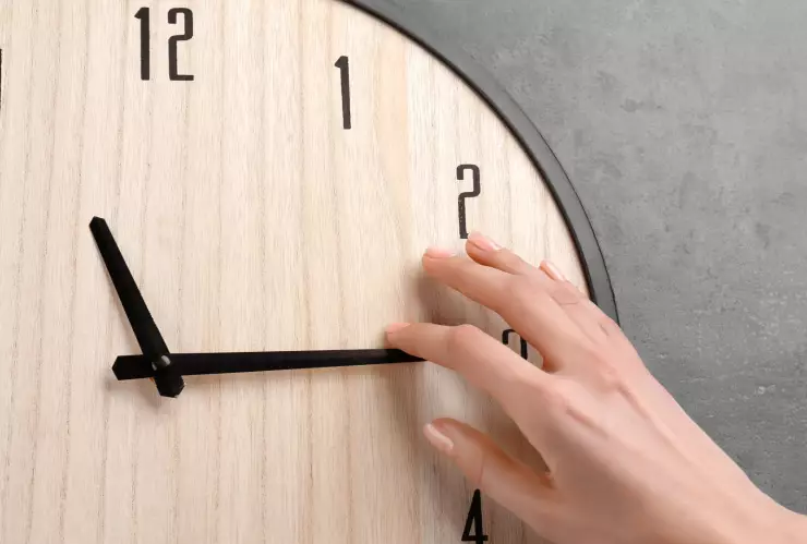 Mano ajusta las manecillas de un reloj por el cambio de horario