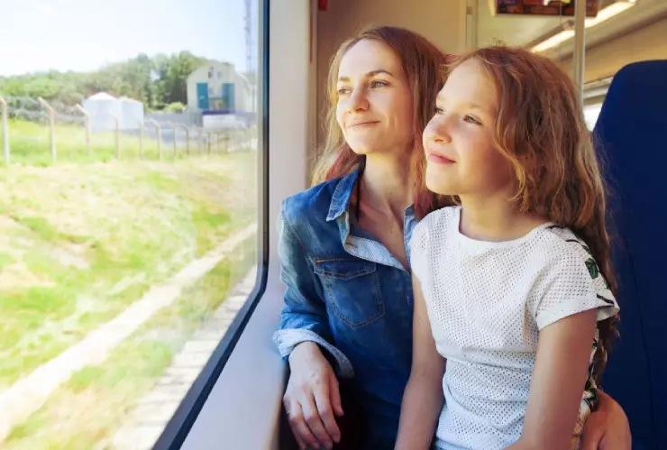 una madre feliz viaja con su niña en tren