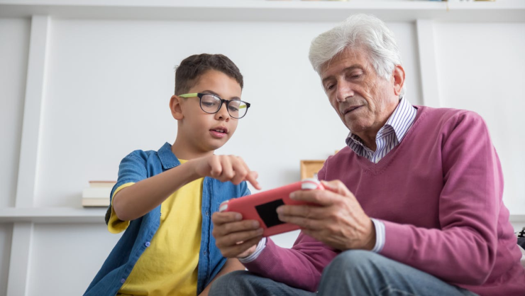 Niño enseñándole a su abuelito cómo empezar su trámite de Mi Pensión Digital IMSS 2025