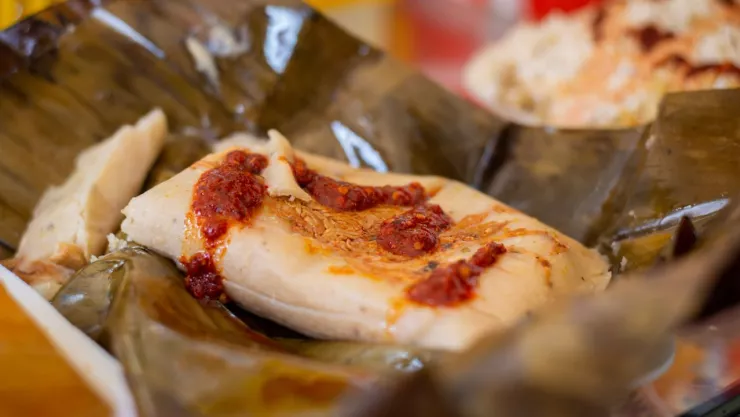 tamal con salsa roja envuelto en hoja de plátano