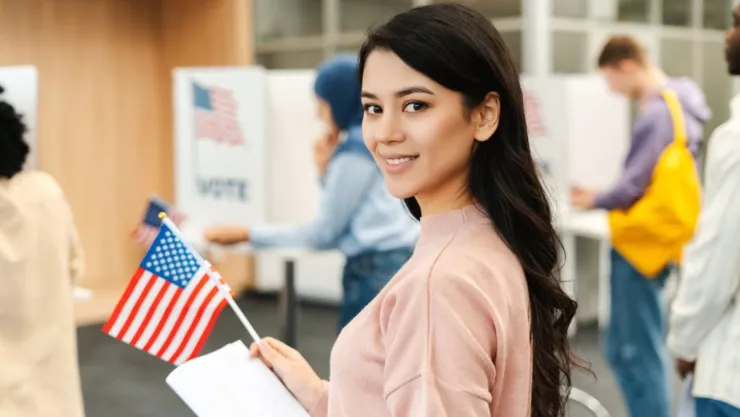 Una mujer va a votar con una bandera de Estados Unidos.