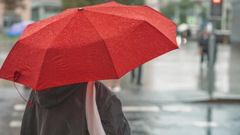Una persona con paraguas bajo la lluvia.