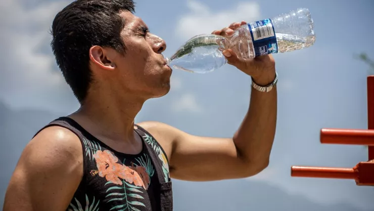 Un hombre tomando agua para refrescarse en medio de una ola de calor.