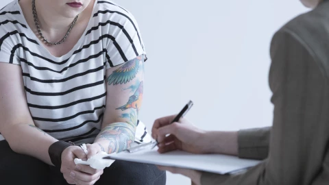 Una mujer con tatuajes en una entrevista consular