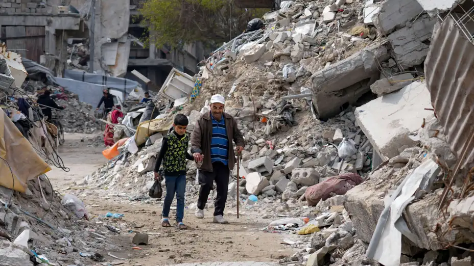 Personas caminan entre viviendas destruidas en Jabaliya.
