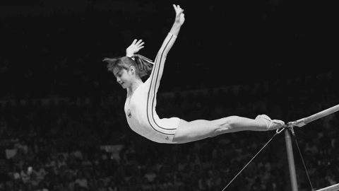 Nadia Comaneci, of Romania, dismounts from the uneven parallel bars at the Olympic Games in Montreal