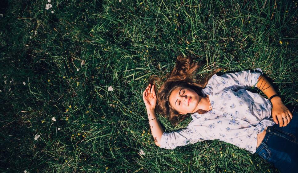 mujer recostada en el pasto con los ojos cerrados