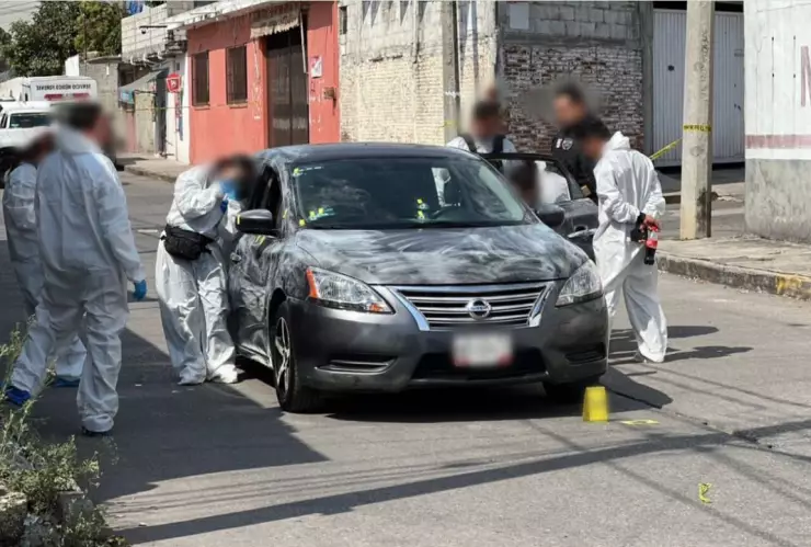 Peritos investigan auto en donde se encontraron los cuerpos de tres mujeres sin vida tras ataque armado.