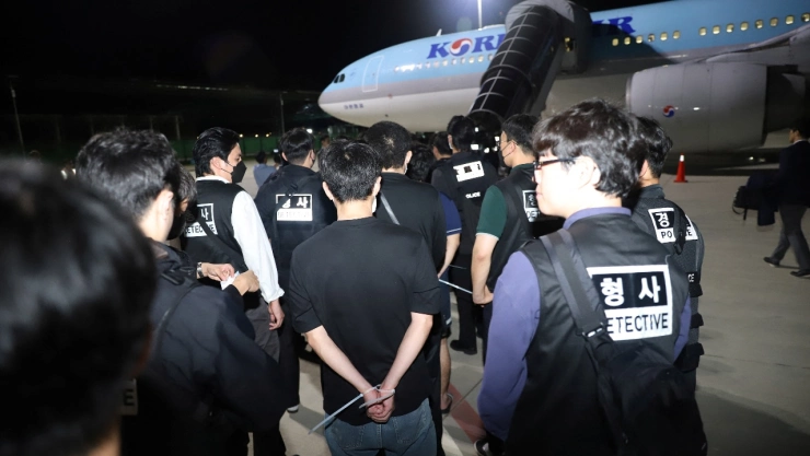 Agentes de la policía surcoreana escoltan a ciudadanos surcoreanos sospechosos de participar en estafas en línea antes de abordar un avión de Korean Air en el Aeropuerto Internacional de Techo, provincia de Kandal, Camboya, el 18 de octubre de 2025.