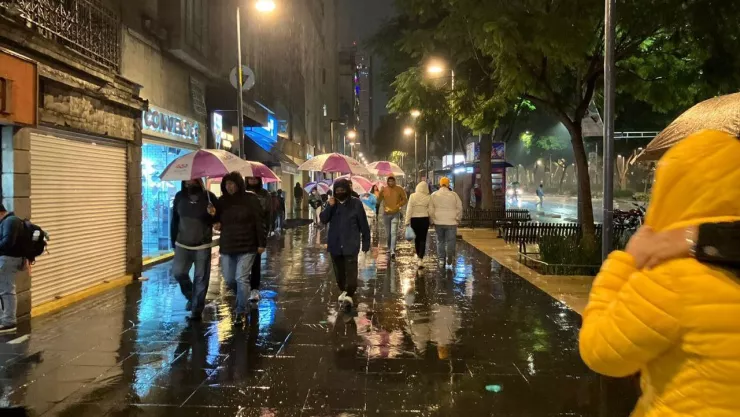 personas caminando bajo la lluvia con su paraguas