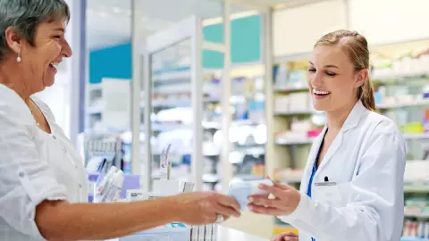 una mujer joven atiende amablemente como empleada farmac&eacute;utica