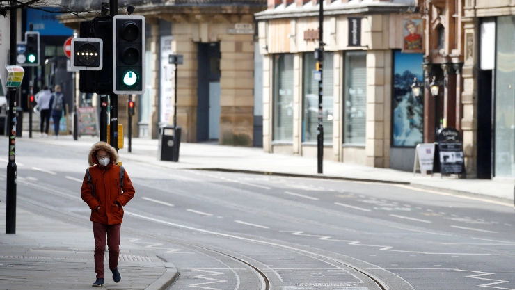 FOTO DE ARCHIVO: Un hombre usa una mascarilla mientras camina por una calle desierta en medio del brote de coronavirus en Manchester, Gran Bretaña.