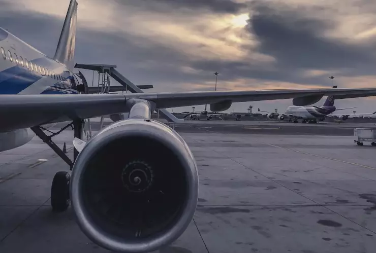 Avión en aeropuerto. Se enfoca una de sus alas y turbinas