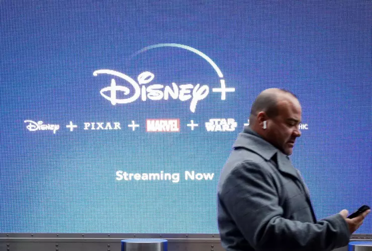 FOTO DE ARCHIVO: Un hombre mira su teléfono cuando pasa por una pantalla que anuncia el servicio de ‘streaming’ de Walt Disney, Disney+, en Nueva York.