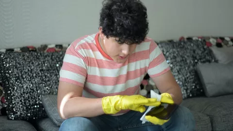 Una persona limpiando celular con alcohol