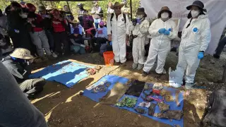 Grupo de personas al rededor de una lona con varios objetos encontrados