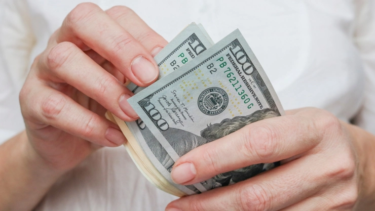 Una persona cuenta billetes de 100 dólares.