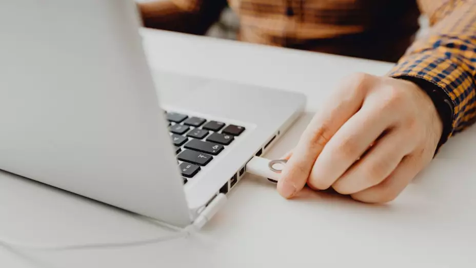 Mano ingresando una USB a una laptop.