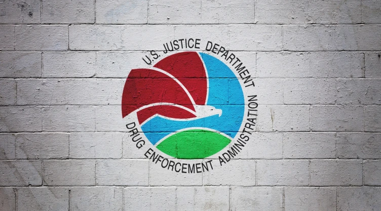 Escudo de la DEA pintado en pared de ladrillos blancos