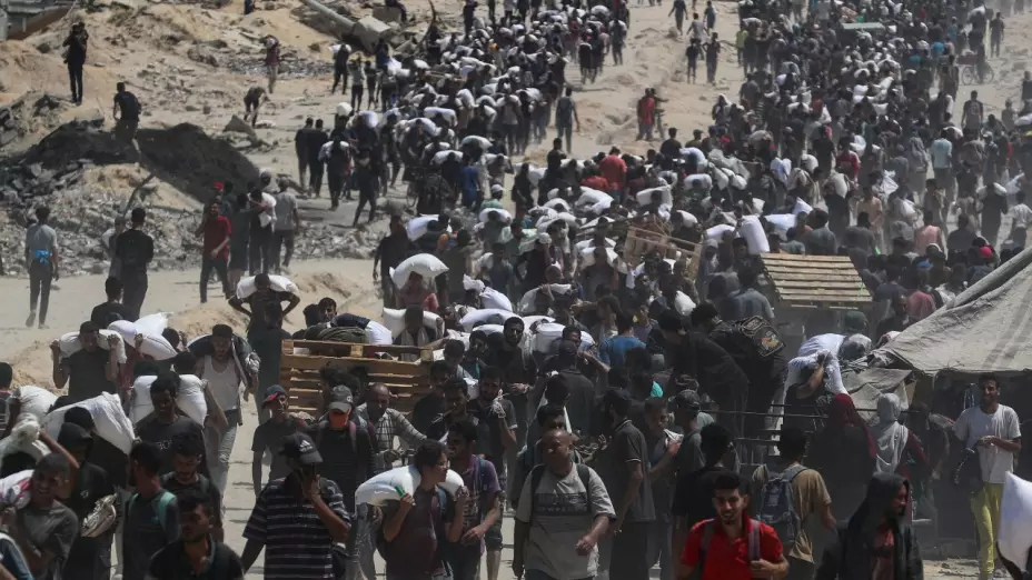 Decenas de personas cargan con costales de ayuda humanitaria en Gaza.