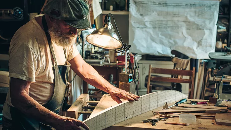 Old bearded man building wooden ship models