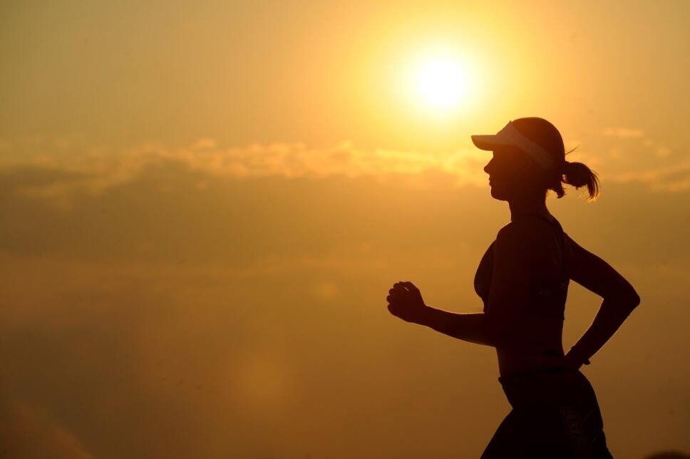 mujer corriendo contra la puesta del sol para bajar de peso y dormir mejor