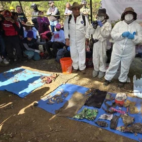 Grupo de personas al rededor de una lona con varios objetos encontrados