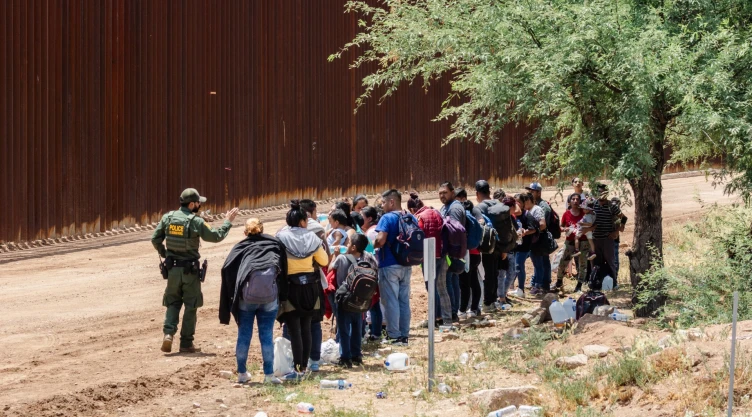 Un grupo de migrantes frente a un policía en la frontera entre México y el estado de Arizona.